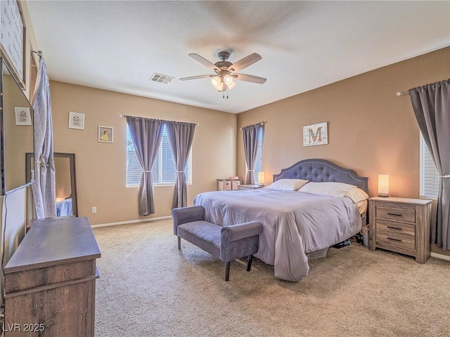 bedroom featuring baseboards, visible vents, a ceiling fan, and light colored carpet