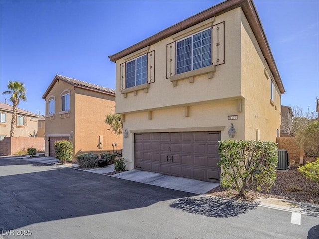 view of front of property with driveway, an attached garage, cooling unit, and stucco siding