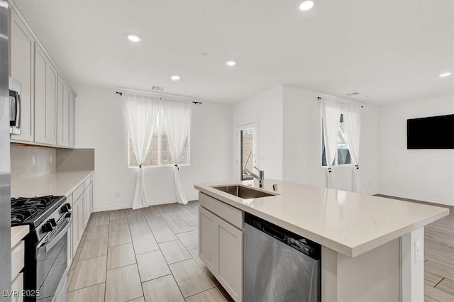 kitchen featuring backsplash, a sink, gas range oven, light countertops, and stainless steel dishwasher