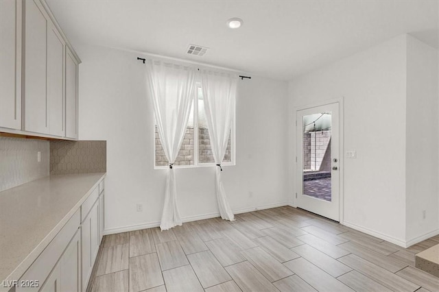 unfurnished dining area with baseboards, visible vents, and wood finish floors