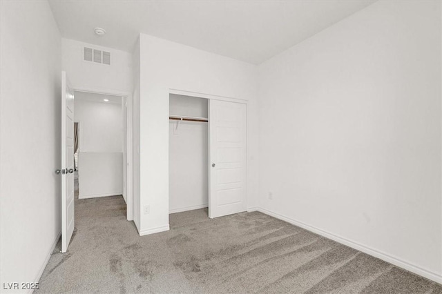 unfurnished bedroom with a closet, carpet, visible vents, and baseboards