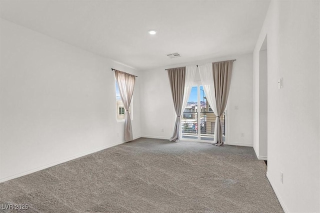 spare room featuring carpet flooring, visible vents, and baseboards