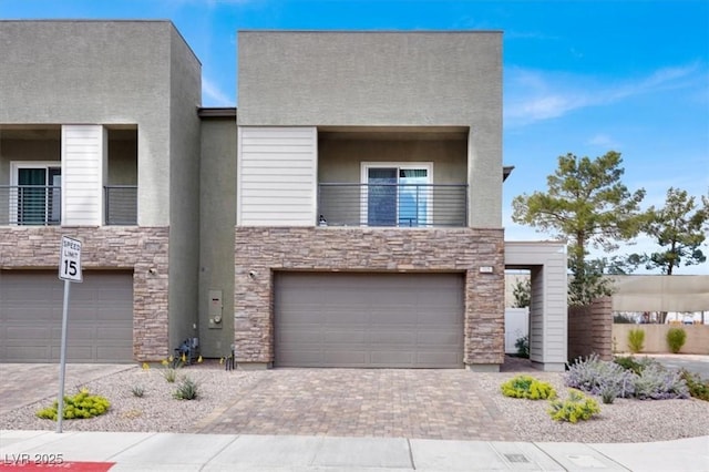 view of front of home featuring driveway, an attached garage, a balcony, and stucco siding