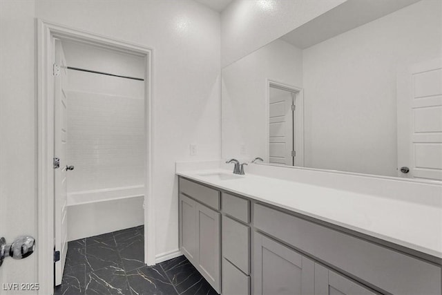 full bathroom with marble finish floor, washtub / shower combination, and vanity