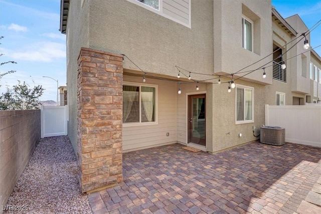 rear view of house featuring cooling unit, stucco siding, fence, and a patio