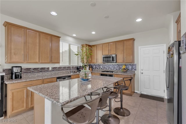 kitchen with light stone counters, a center island, a breakfast bar, stainless steel appliances, and decorative backsplash