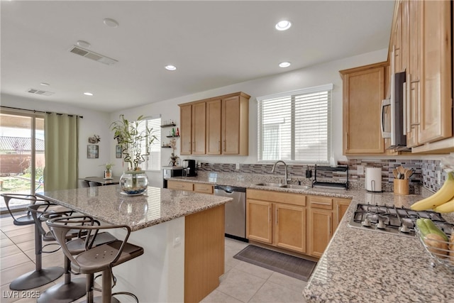 kitchen featuring plenty of natural light, visible vents, appliances with stainless steel finishes, a kitchen breakfast bar, and a sink