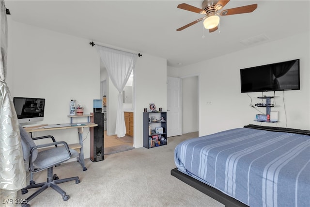 bedroom with ceiling fan, ensuite bathroom, and light colored carpet