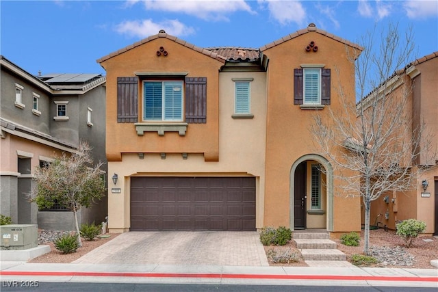 mediterranean / spanish home featuring a tiled roof, a garage, driveway, and stucco siding