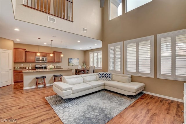 living area featuring recessed lighting, baseboards, visible vents, and light wood finished floors