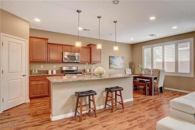 kitchen with a sink, stainless steel appliances, light wood-style floors, and visible vents