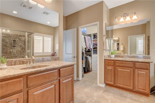 full bath with a stall shower, two vanities, visible vents, and a sink