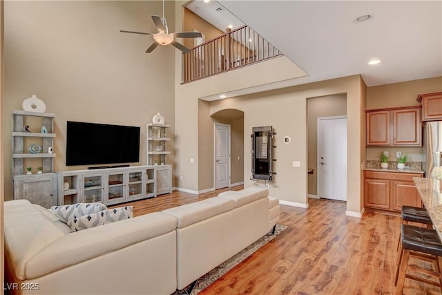 living room featuring recessed lighting, arched walkways, light wood-style floors, baseboards, and ceiling fan