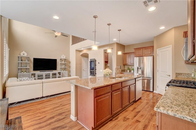 kitchen with visible vents, open floor plan, light wood-style flooring, appliances with stainless steel finishes, and a sink