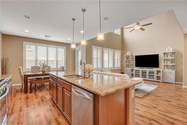 kitchen featuring brown cabinetry, open floor plan, stainless steel appliances, and light wood-style floors