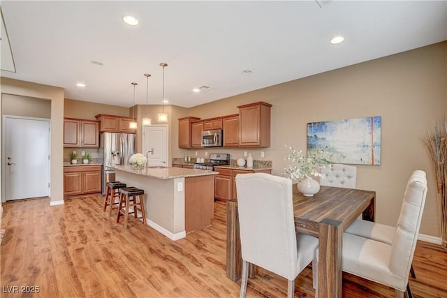 kitchen with a kitchen island, recessed lighting, stainless steel appliances, a kitchen breakfast bar, and light wood-type flooring