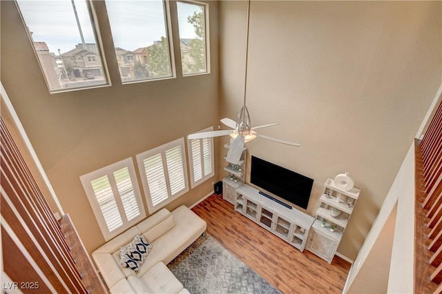 living area featuring a ceiling fan, plenty of natural light, and wood finished floors