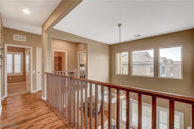 hall with plenty of natural light, light wood-style floors, and visible vents