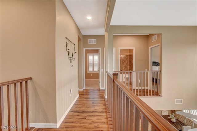 hallway featuring an upstairs landing, visible vents, light wood-type flooring, and baseboards