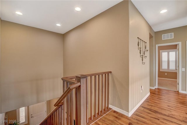 hall featuring visible vents, light wood finished floors, baseboards, recessed lighting, and an upstairs landing