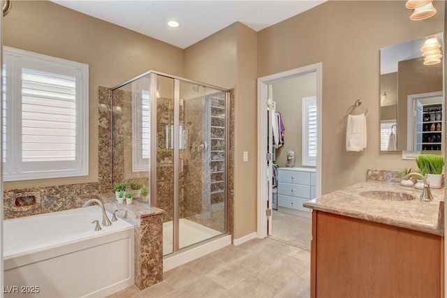 bathroom with vanity, a shower stall, a bath, and a wealth of natural light