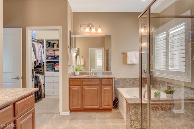 full bathroom with tile patterned floors, a walk in closet, a stall shower, a bath, and vanity