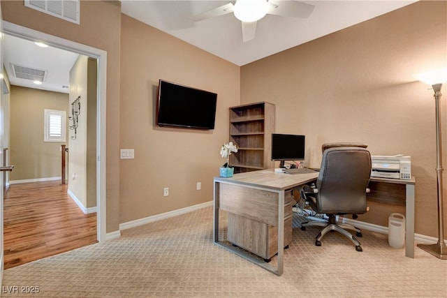 carpeted office with baseboards, visible vents, and ceiling fan