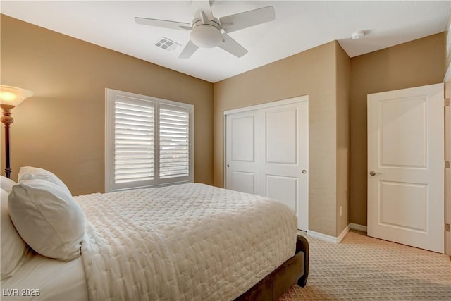 bedroom featuring visible vents, a ceiling fan, a closet, baseboards, and light colored carpet