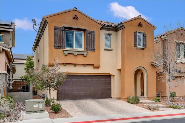 mediterranean / spanish house with stucco siding, decorative driveway, a garage, and a tiled roof