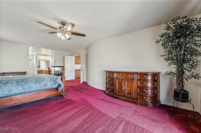 bedroom featuring ceiling fan, connected bathroom, baseboards, and dark colored carpet