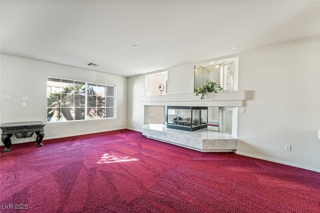 carpeted living area featuring visible vents, baseboards, and a high end fireplace