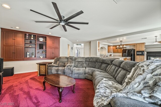 living area featuring carpet, a ceiling fan, baseboards, recessed lighting, and arched walkways