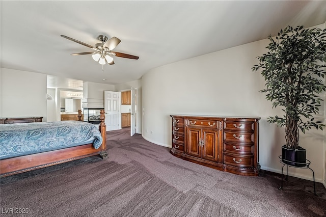bedroom with ensuite bathroom, baseboards, dark carpet, and ceiling fan
