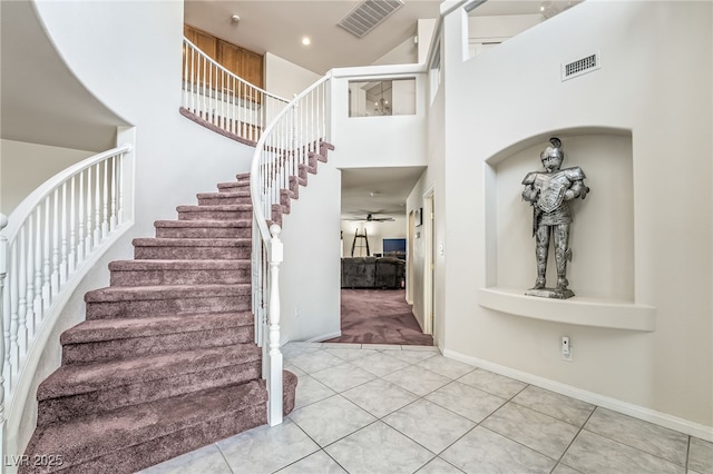 stairs with tile patterned flooring, carpet flooring, a towering ceiling, and visible vents