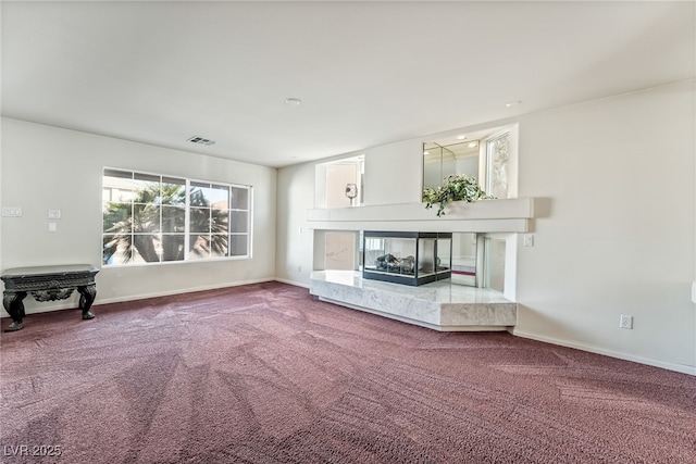 unfurnished living room with a high end fireplace, baseboards, visible vents, and carpet
