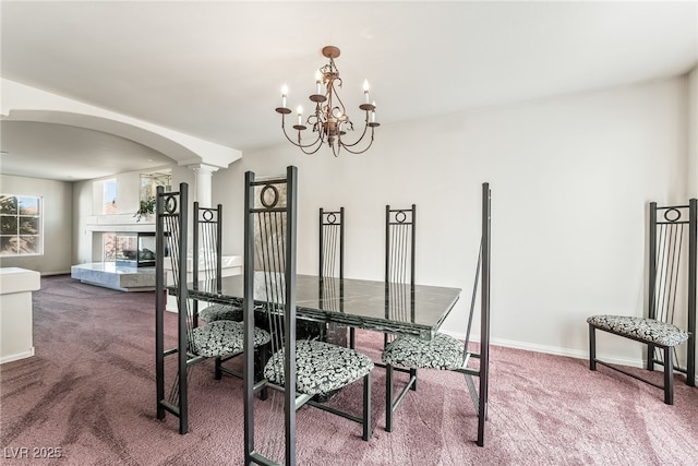 carpeted dining room with arched walkways, a chandelier, baseboards, and decorative columns