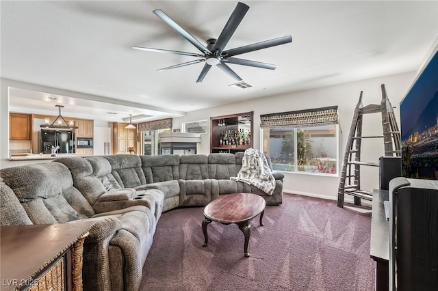 living area with baseboards, visible vents, dark carpet, and ceiling fan