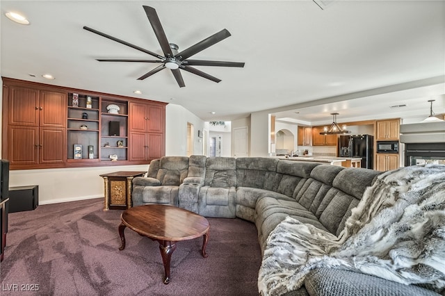 living area featuring arched walkways, a ceiling fan, dark carpet, and recessed lighting