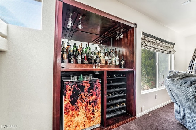bar with a dry bar, baseboards, and carpet flooring