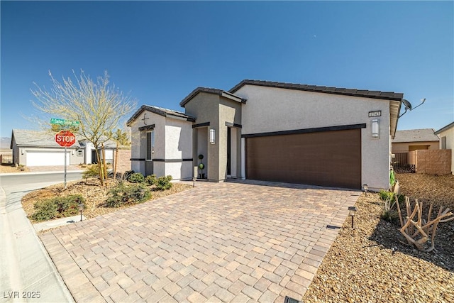 view of front of home featuring decorative driveway, a garage, and stucco siding