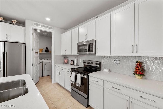 kitchen with backsplash, stainless steel appliances, separate washer and dryer, and white cabinets