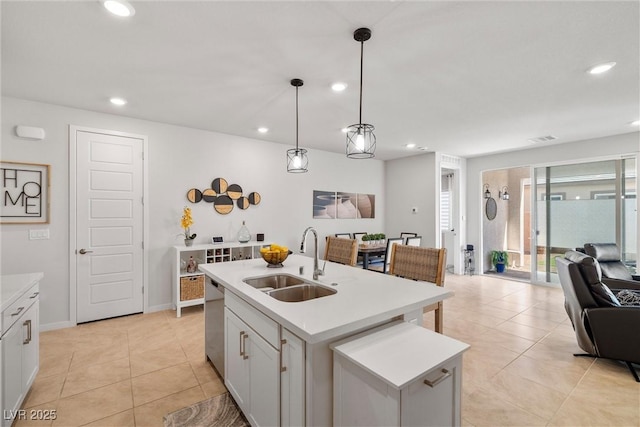 kitchen with open floor plan, dishwasher, light countertops, light tile patterned floors, and a sink