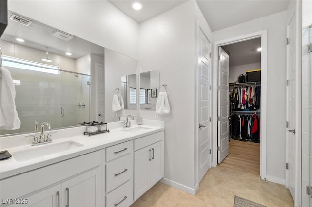 full bathroom featuring double vanity, visible vents, a shower stall, and a sink