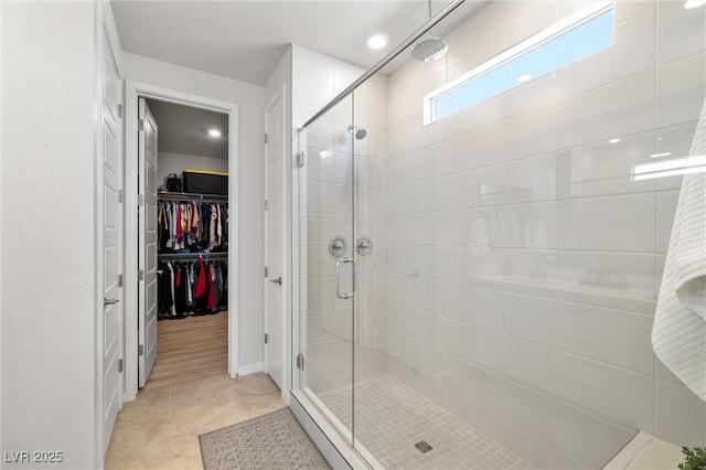 full bathroom with tile patterned flooring, a shower stall, and a spacious closet