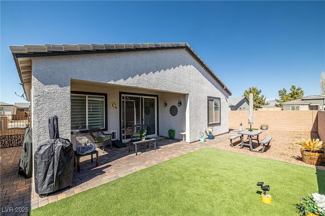 rear view of property with a patio area, stucco siding, a yard, and a fenced backyard