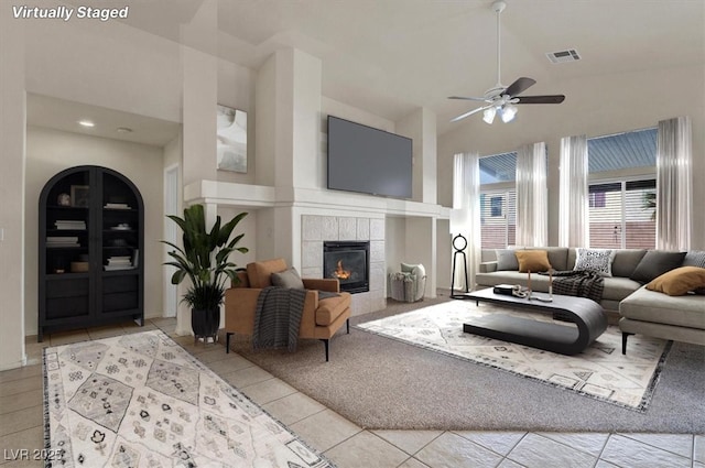 living room featuring visible vents, ceiling fan, a fireplace, high vaulted ceiling, and light tile patterned flooring