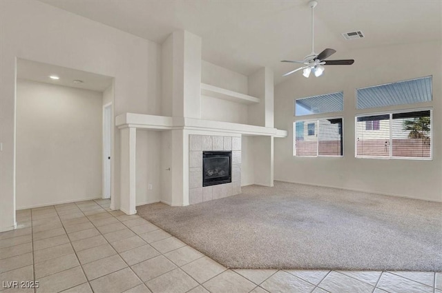 unfurnished living room with ceiling fan, high vaulted ceiling, light carpet, a fireplace, and visible vents