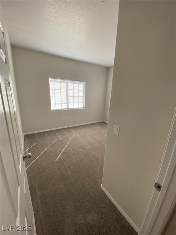 unfurnished room with baseboards, dark colored carpet, and a textured ceiling