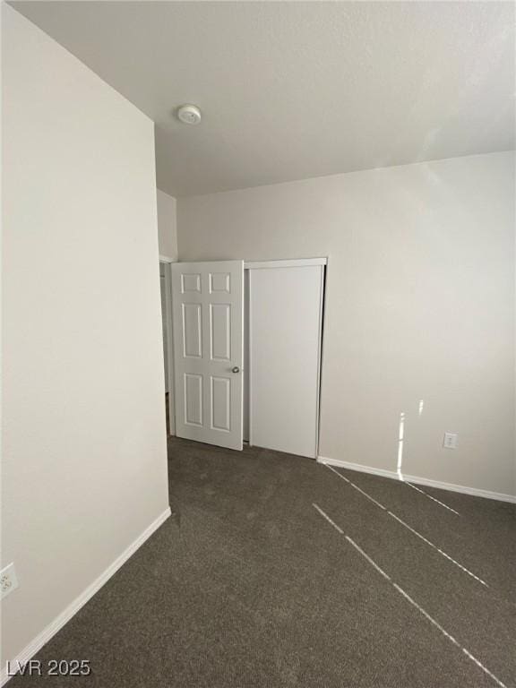 empty room with dark carpet and baseboards