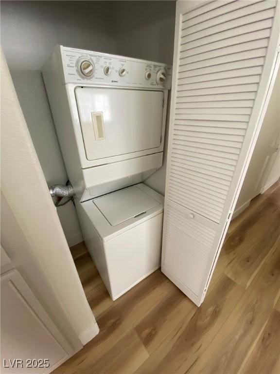 laundry room with stacked washing maching and dryer, laundry area, and wood finished floors